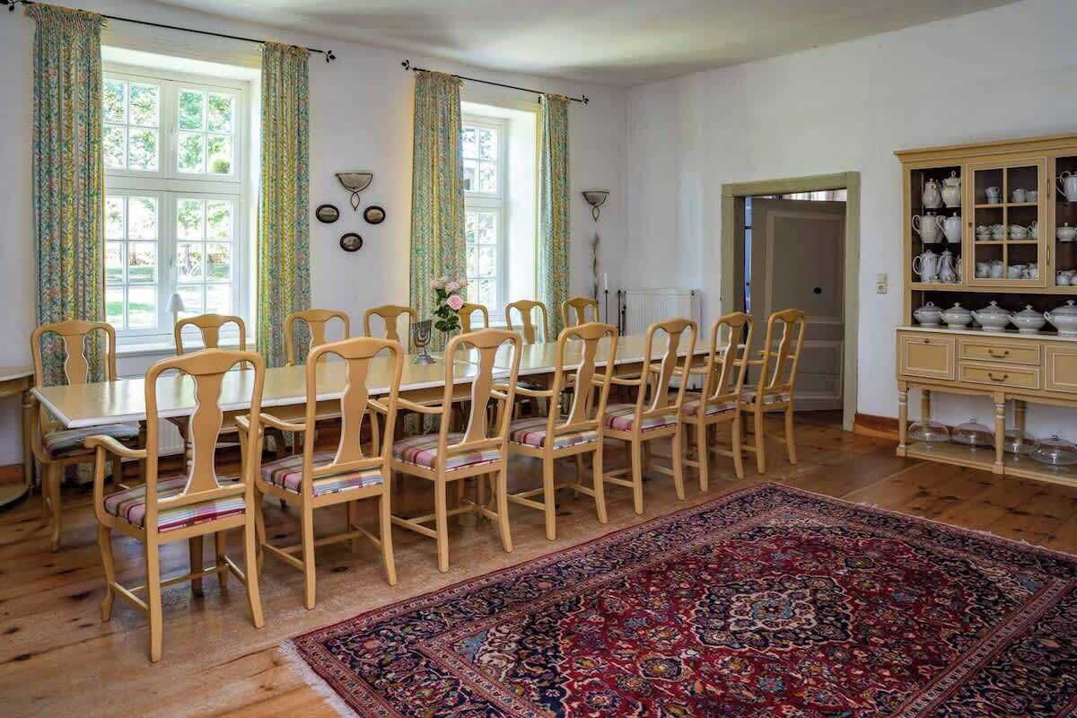 Une salle à manger avec une table et des chaises en bois, un tapis à motifs et un buffet.