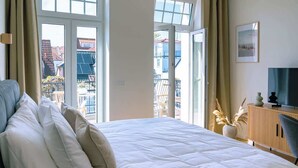 Un dormitorio con una cama grande, televisor y vistas al exterior.