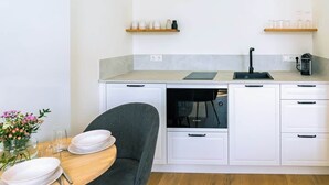 Una cocina moderna con armarios blancos, un lavavajillas Bosch y una mesa de comedor de madera con platos y un jarrón de flores.