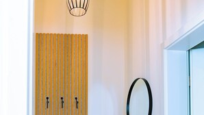 Un couloir avec une porte à lambris en bois, un miroir rond et un luminaire suspendu.