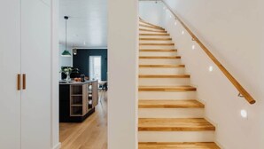A modern interior with a wooden staircase and a kitchen area visible in the background. - Aloha Pruchten (Pruchten)