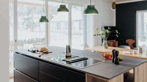 A modern kitchen with a central island, black cabinets, and a stainless steel sink. - Aloha Pruchten (Pruchten)