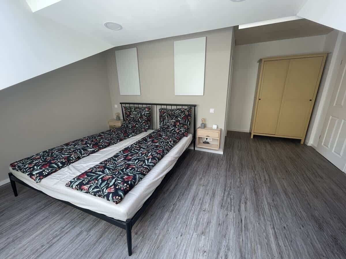Un dormitorio con cama, mesita de noche, armario y tragaluz.
