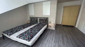 Un dormitorio con cama, mesita de noche, armario y tragaluz.