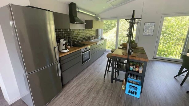 A modern kitchen with a stainless steel refrigerator, a built-in oven, and a wooden island with stools. - "Smart Apartment" Heidelberg (Heidelberg)