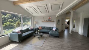 A spacious living room with a large window, a sectional sofa, a coffee table, and a wooden ceiling. - "Smart Apartment" Heidelberg (Heidelberg)