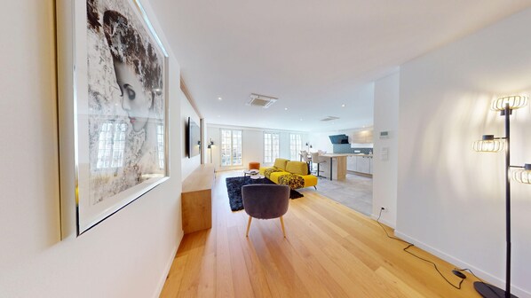 Uma sala de estar moderna com um grande quadro abstrato, um sofá amarelo e piso de madeira.