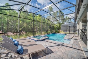 Una piscina exterior cubierta con sillas de descanso y un jacuzzi, rodeada por una estructura metálica y árboles.
