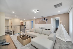 A modern living room with a beige sofa, a glass coffee table, and a white tent-like structure.