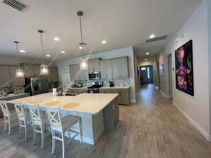 A modern kitchen with a large island, white cabinetry, stainless steel appliances, and pendant lighting. - Go 10 - 15530 WG in Winter Garden (Winter Garden)