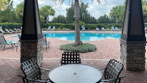 A covered outdoor area with a pool, lounge chairs, and a table. - Go 10 - 15530 WG in Winter Garden (Winter Garden)
