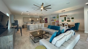 A modern living room with a grey sofa, a coffee table, and a dining area in the background. - Go 10 - 15530 WG in Winter Garden (Winter Garden)