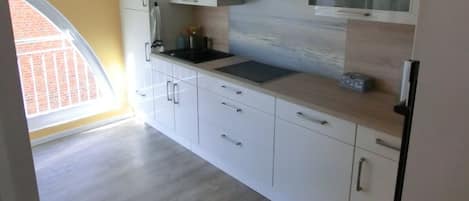 A modern kitchen with white cabinetry, a black countertop, and a built-in microwave.