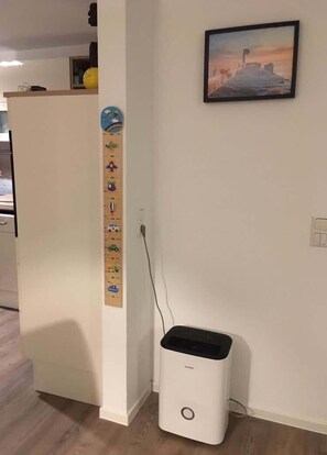 A kitchen with a white refrigerator, a small trash bin, and a wall-mounted calendar. - Stralsund Altstadt, 2-Zi-Wohnung mit Loggia (Stralsund)