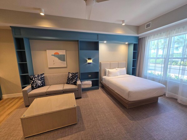 Une chambre d’hôtel moderne équipée d’un lit, d’un canapé, d’une table basse et d’une étagère fixée au mur.