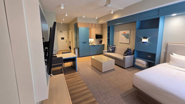 A modern hotel room with a bed, a sofa, a dining table, and a kitchenette. - Go 29 Margaritaville Studio (Kissimmee)
