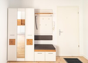 A room with a wardrobe, a bench, and a door.