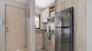 A modern kitchen with a stainless steel refrigerator, wooden cabinets, and a tiled floor.