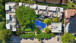 An aerial view of a residential complex with multiple buildings, a swimming pool, and surrounding greenery.