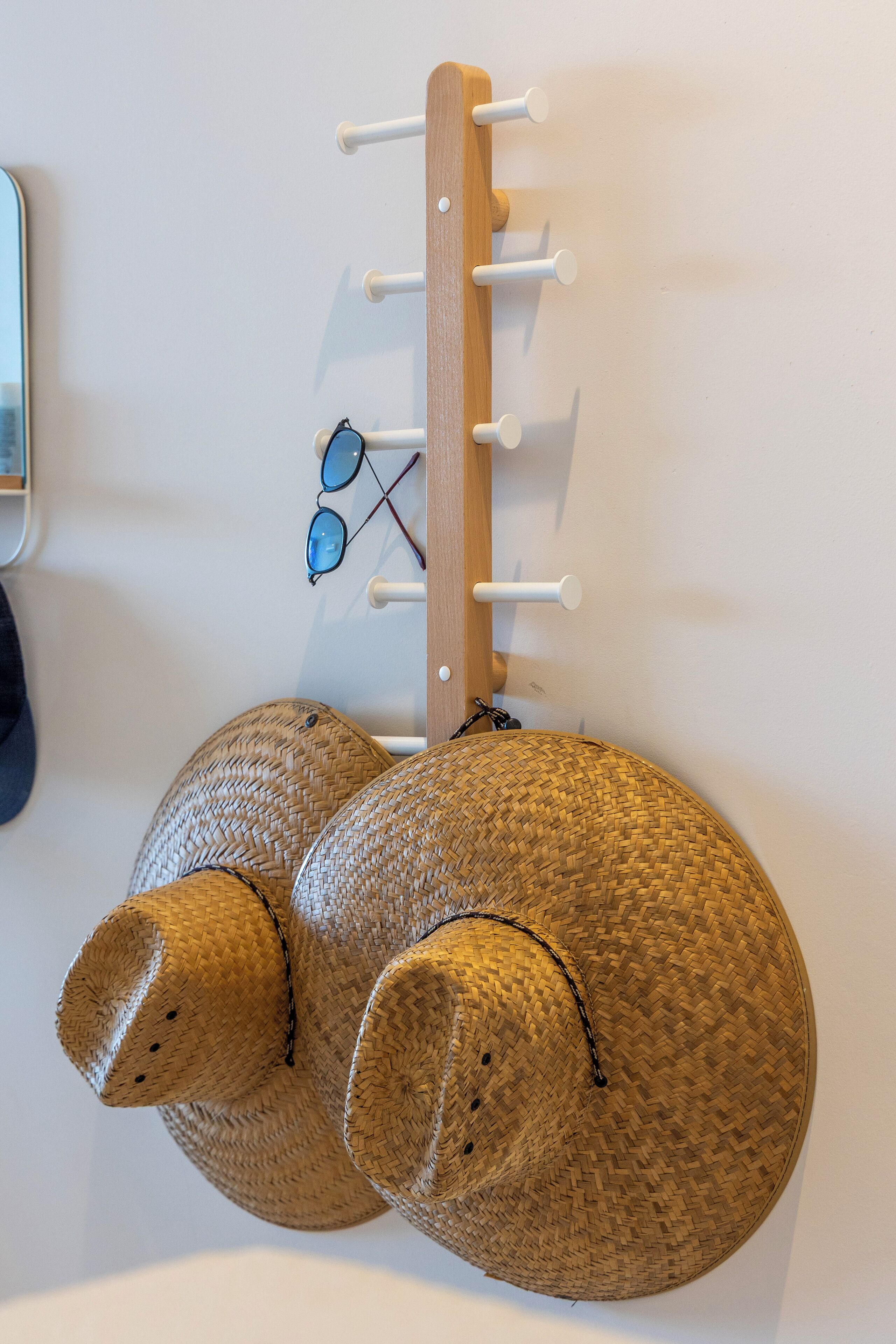 Eine Wandhalterung mit Haken, an denen eine Sonnenbrille hängt.