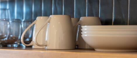 A kitchen counter with various ceramic mugs and bowls.