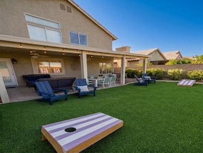 A house with a covered patio area, outdoor seating, and a well-maintained lawn.
