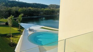 Un espace piscine extérieur moderne offrant une vue dégagée sur un lac et des collines en arrière-plan.
