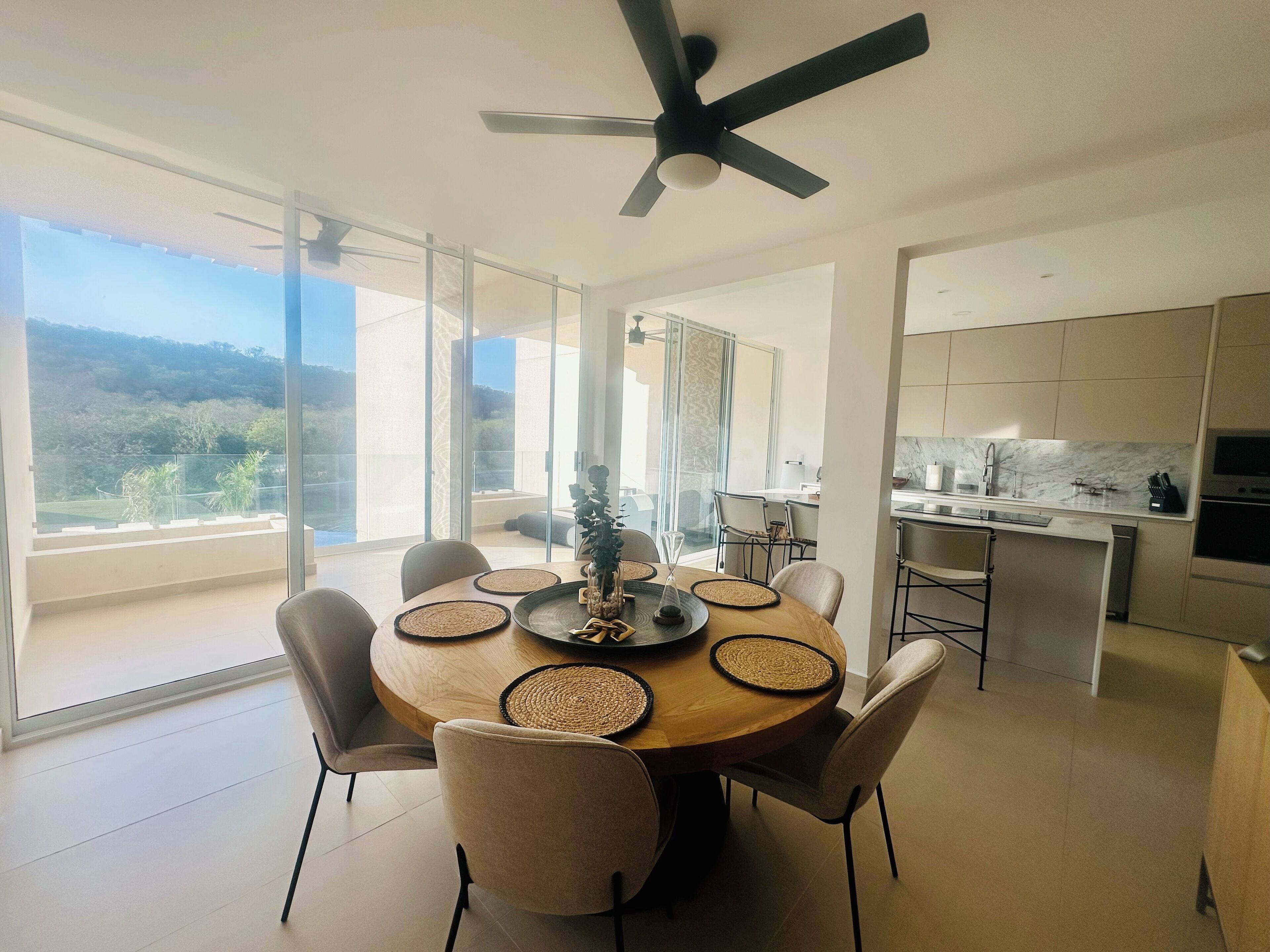 A modern dining area with a round table, chairs, and a ceiling fan.