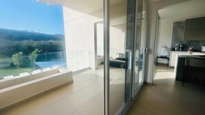 Un appartement moderne doté d’un balcon, d’une cuisine et offrant une vue sur un paysage verdoyant.