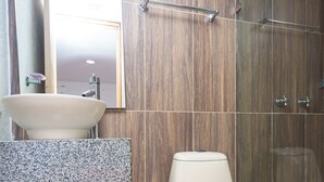 Un baño con lavamanos, espejo, inodoro y zona de ducha.