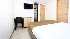 Un dormitorio con cama, escritorio, silla, televisor y armario.