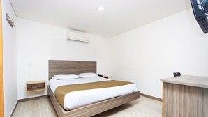 Una habitación de hotel moderna con cama, mesita de noche y escritorio.