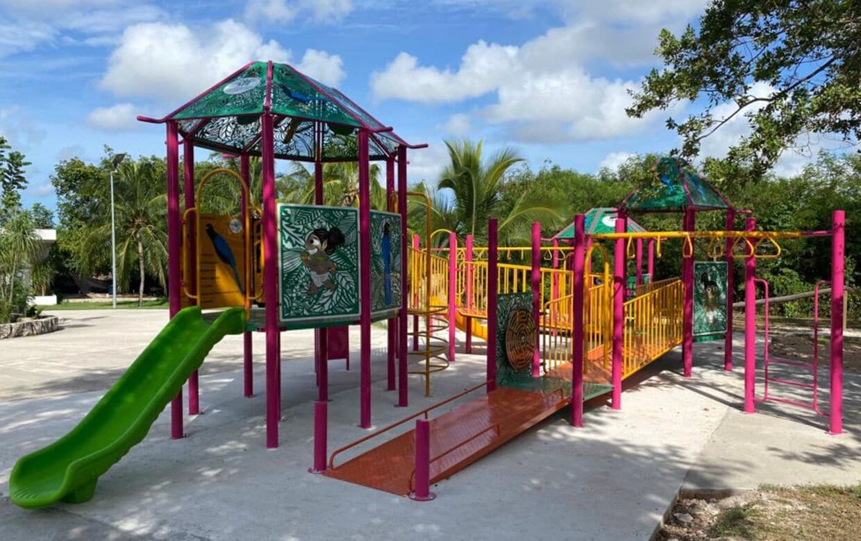 A playground with a green slide, climbing structures, and a covered play area.