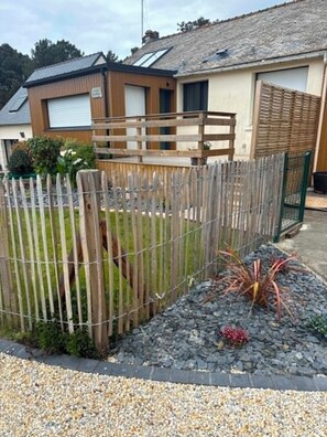 A residential area with a wooden fence, a house with a garage, and a garden with gravel and plants.