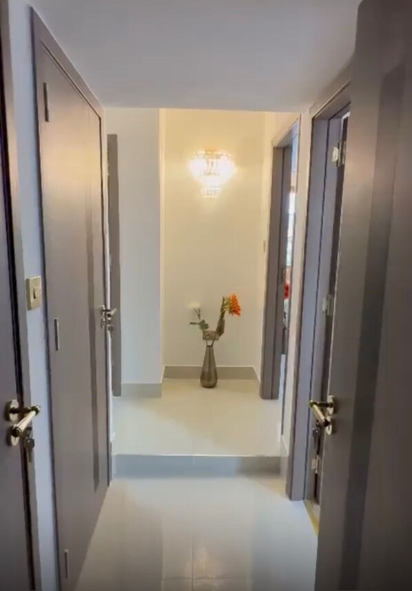 Ein Flur mit einem Blumenstrauß auf dem Boden, einer Leuchte an der Decke und Türen auf beiden Seiten.