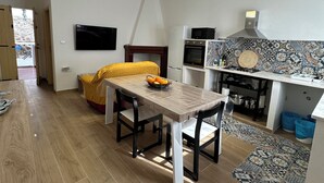 Een moderne keuken met een eethoek, een aan de muur bevestigde televisie en een decoratieve spatwand.