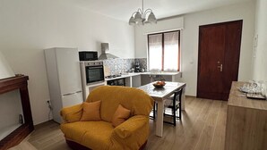 Een compacte woonruimte met een kitchenette, een eethoek en een bank.