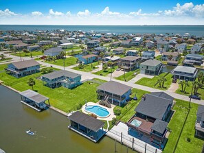 A residential area with houses, a swimming pool, and a dock. - Purple Pelican Paradise by Ryson Vacation Rentals (Galveston)