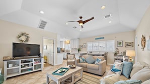 A spacious living room with a television, sofa, and coffee table. - Purple Pelican Paradise by Ryson Vacation Rentals (Galveston)