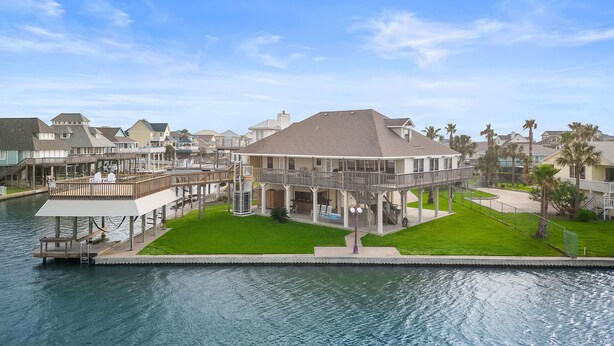 A waterfront property with a large house featuring a covered patio and a pool.