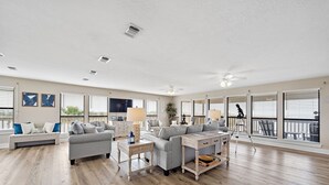 A spacious living room with a grey sofa, a wooden coffee table, and a TV.