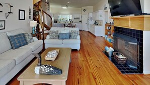 A spacious living area with a wooden floor, a sofa, a coffee table, and a fireplace. - Casablanca by Ryson Vacation Rentals (Galveston)