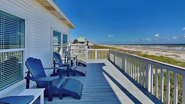 A wooden deck with Adirondack chairs, a white railing, and a view of the beach. - Casablanca by Ryson Vacation Rentals (Galveston)