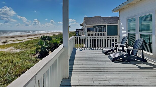 A wooden deck with Adirondack chairs overlooking a beach. - Casablanca by Ryson Vacation Rentals (Galveston)