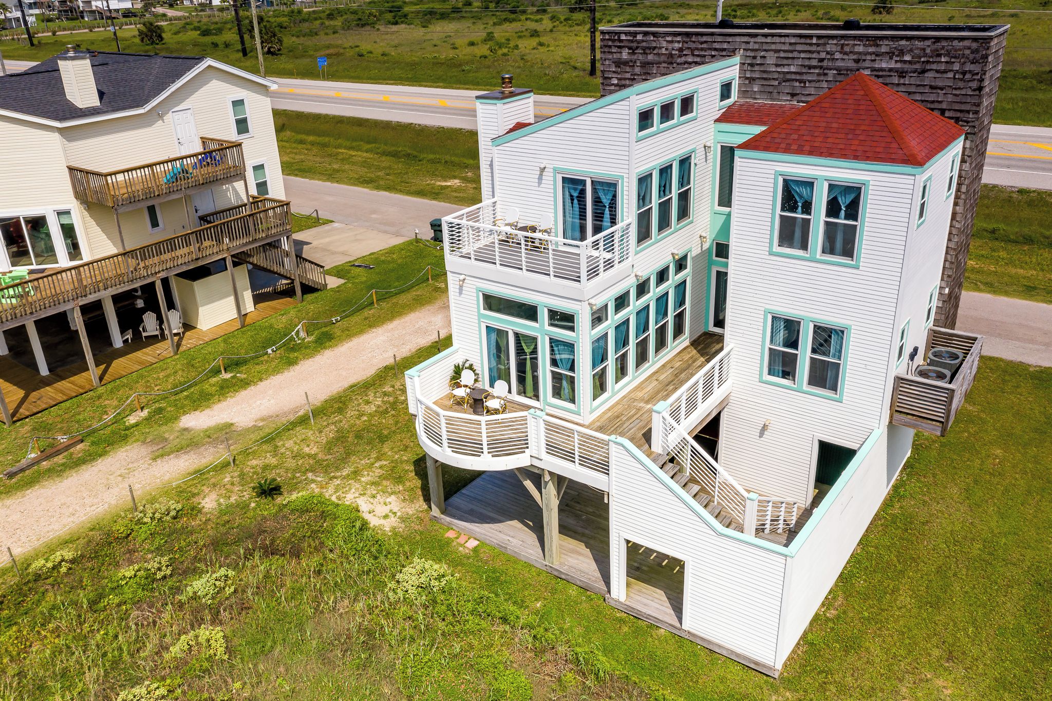 Une maison à plusieurs étages avec un balcon, une terrasse et un toit rouge.