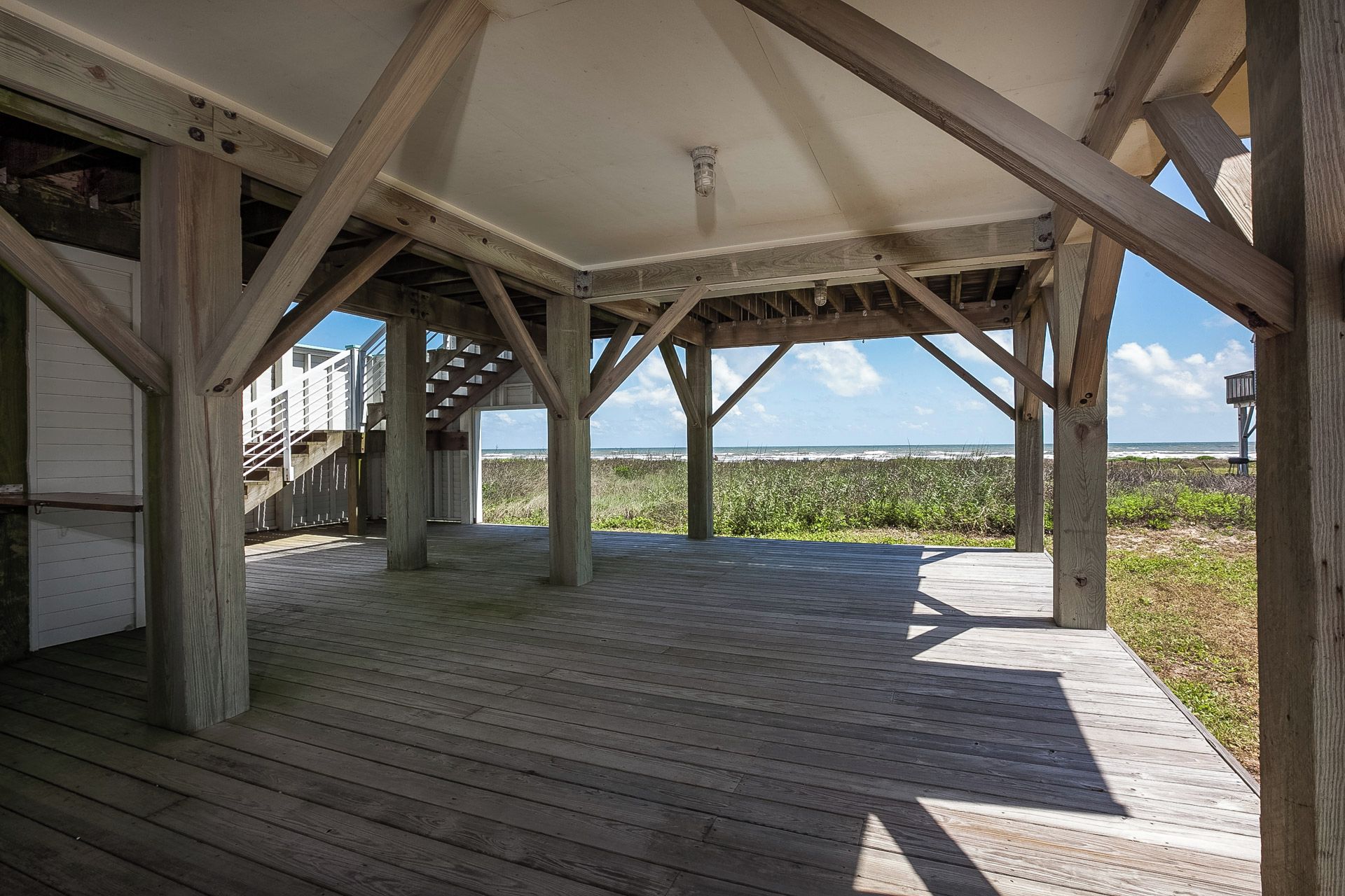 Una terraza de madera abierta con vista a la playa y al océano.