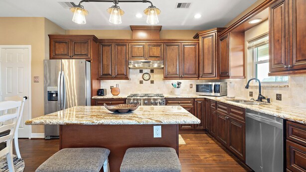 A modern kitchen with wooden cabinets, stainless steel appliances, and a granite countertop. - Copper Top by Ryson Vacation Rentals (Galveston)