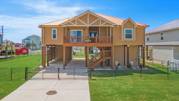 A two-story house with a balcony, a front porch, and a visible garage. - Copper Top by Ryson Vacation Rentals (Galveston)