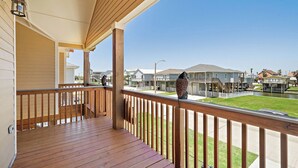 A wooden deck with a railing, overlooking a residential area with houses and a clear sky. - Copper Top by Ryson Vacation Rentals (Galveston)