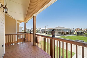 A wooden deck with a railing, overlooking a residential area with houses and a clear sky. - Copper Top by Ryson Vacation Rentals (Galveston)